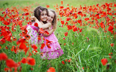 Two girls in a friendship hug in field of flowers.